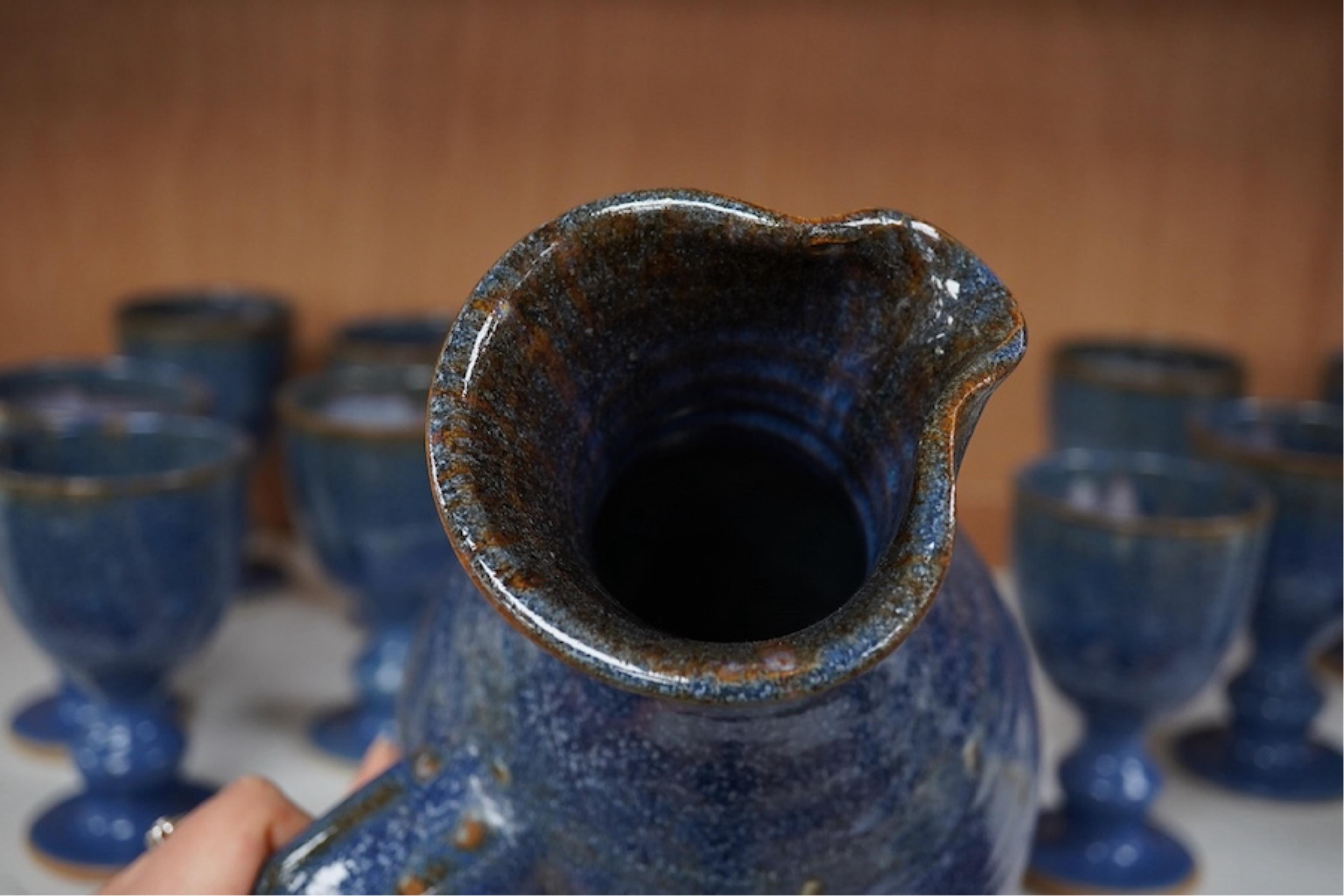 A Canterbury pottery, blue glaze jug and twelve goblets, jug 28cm high. Condition - fine chip to one goblet